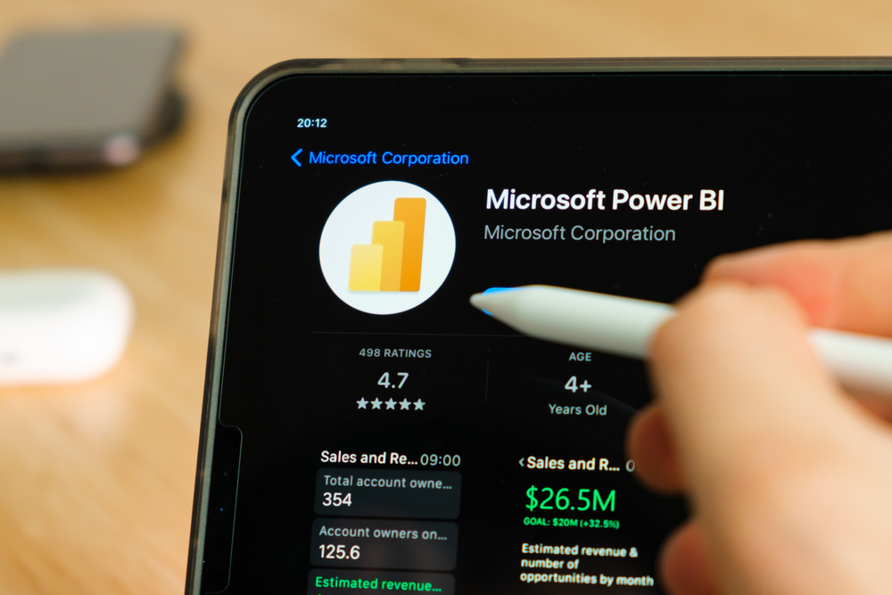 Microsoft Power BI logo shown by apple pencil on the iPad Pro tablet screen. Man using application on the tablet